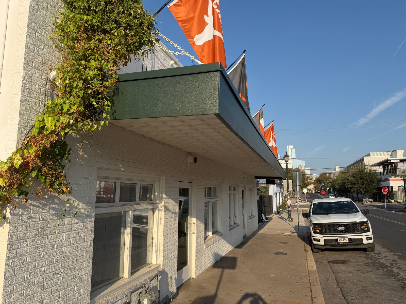 Close view of the new green-painted fascia and drip edge at the end of the canopy over the sidewalk