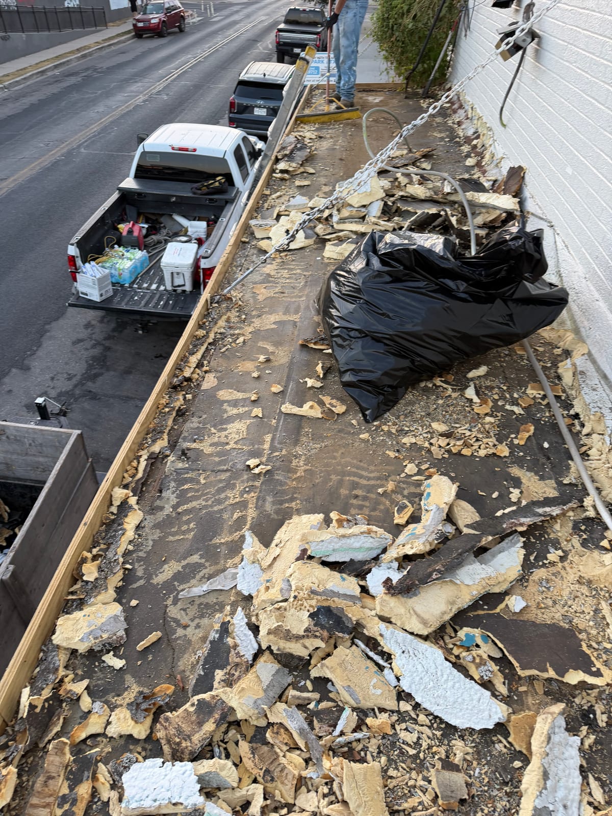 Old canopy roof torn up, with broken foam insulation and debris across the deck above the street