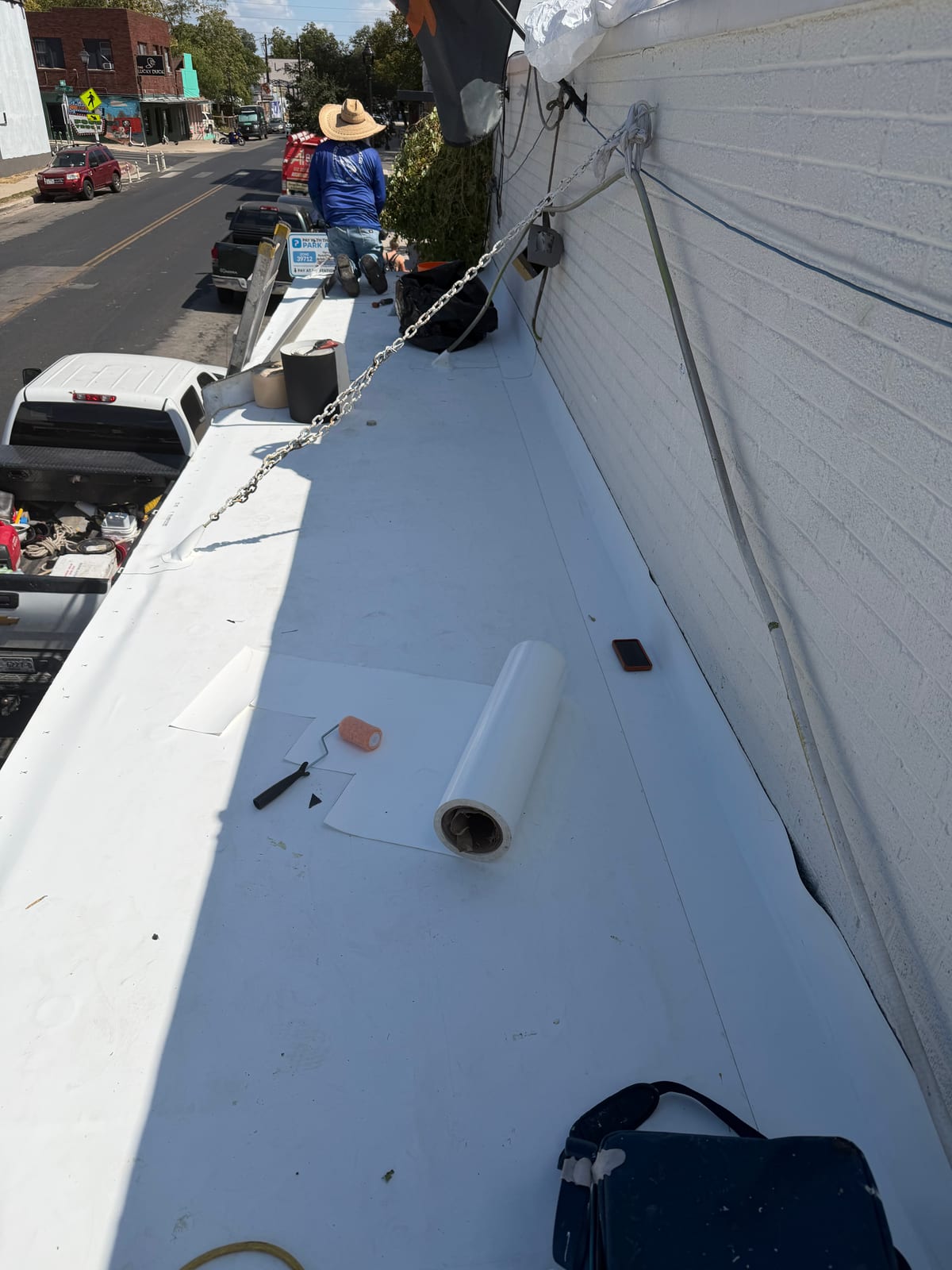 New white TPO membrane laid along the long canopy roof, with a crew member working at the far end