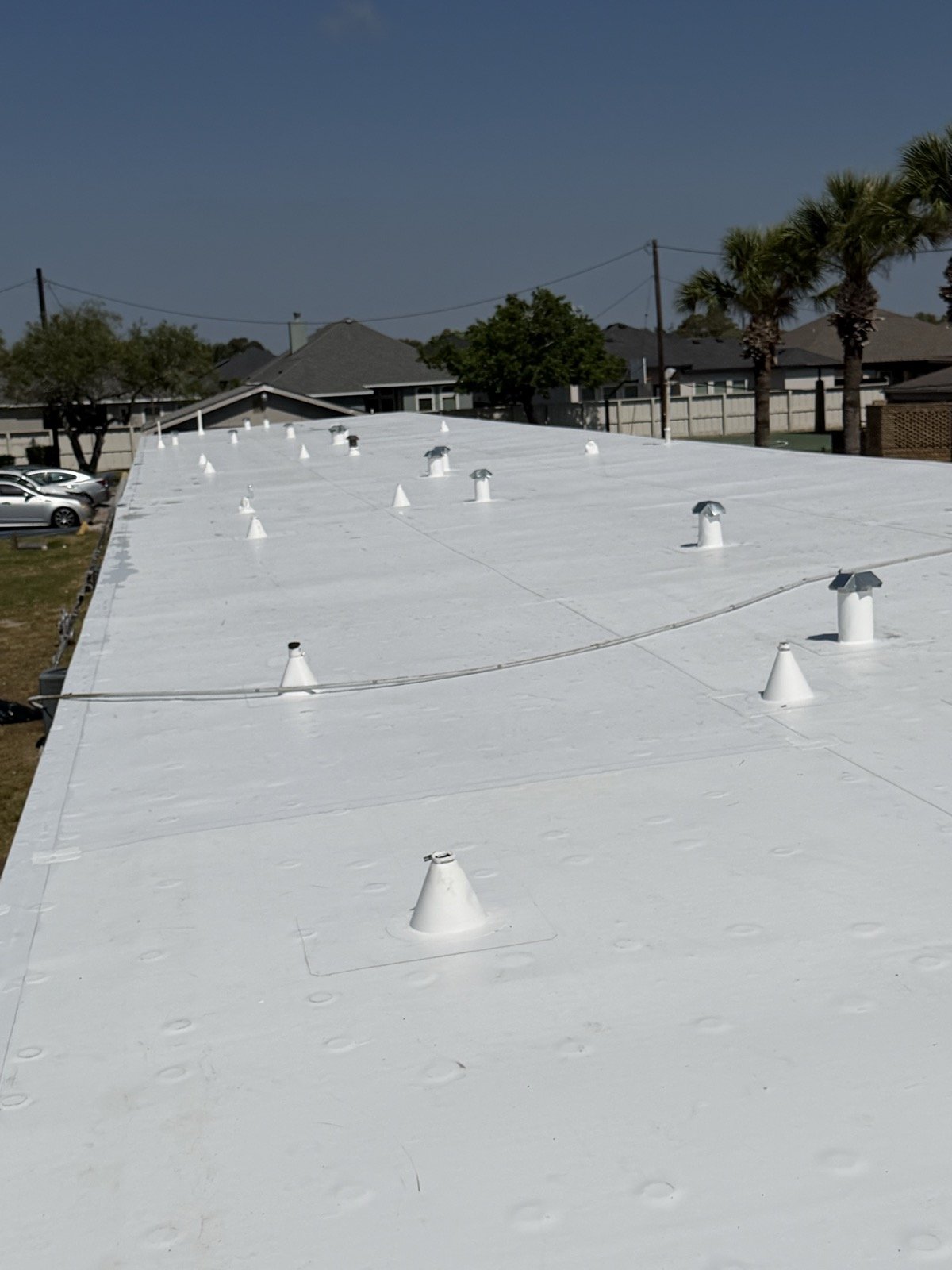 Finished white TPO membrane with flashed vents and pipe boots across the roof