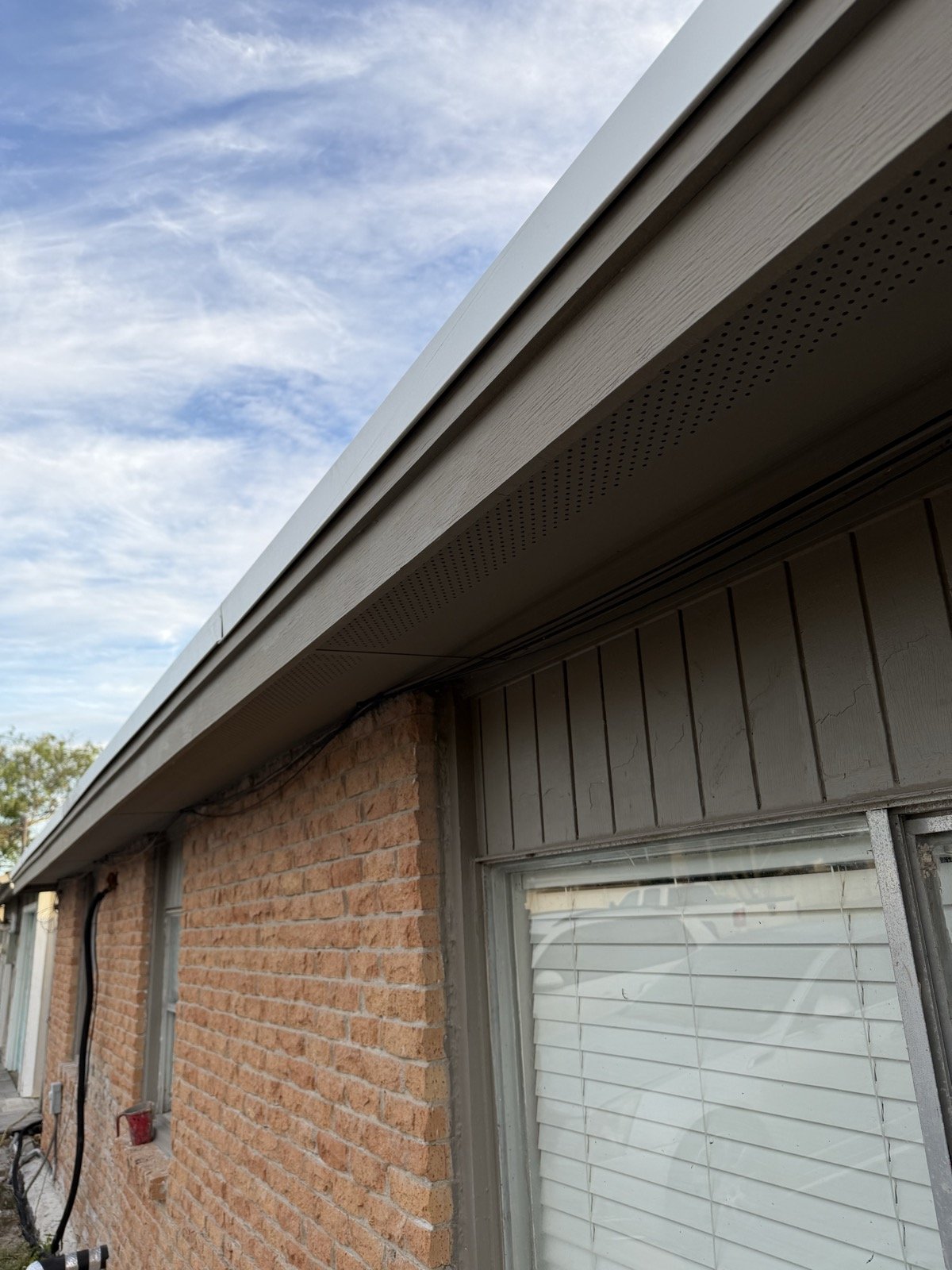 New vented Hardie soffit and fascia installed at the eave above a brick wall