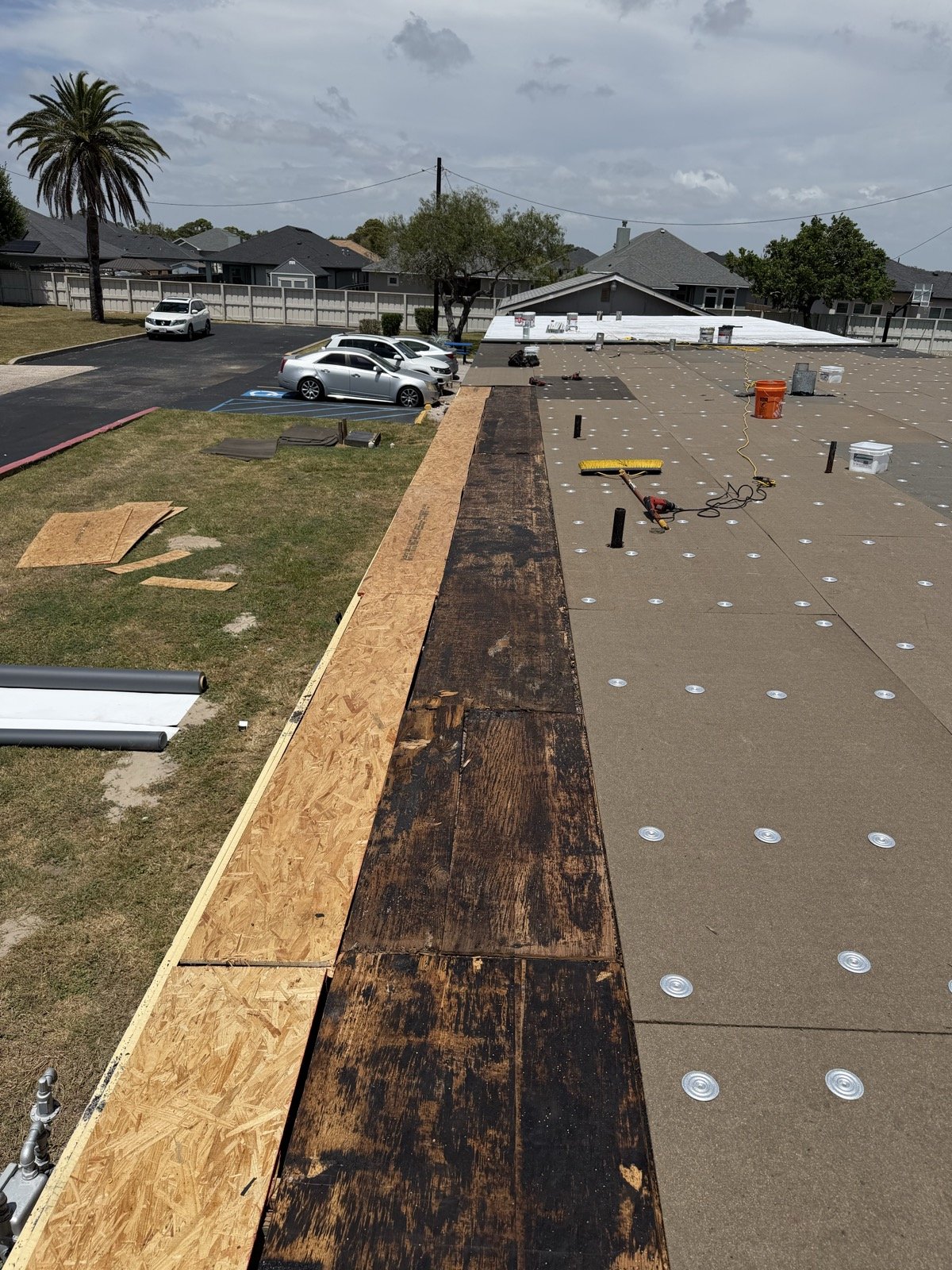 New substrate board fastened with plates across the roof deck, fresh plywood at the edge