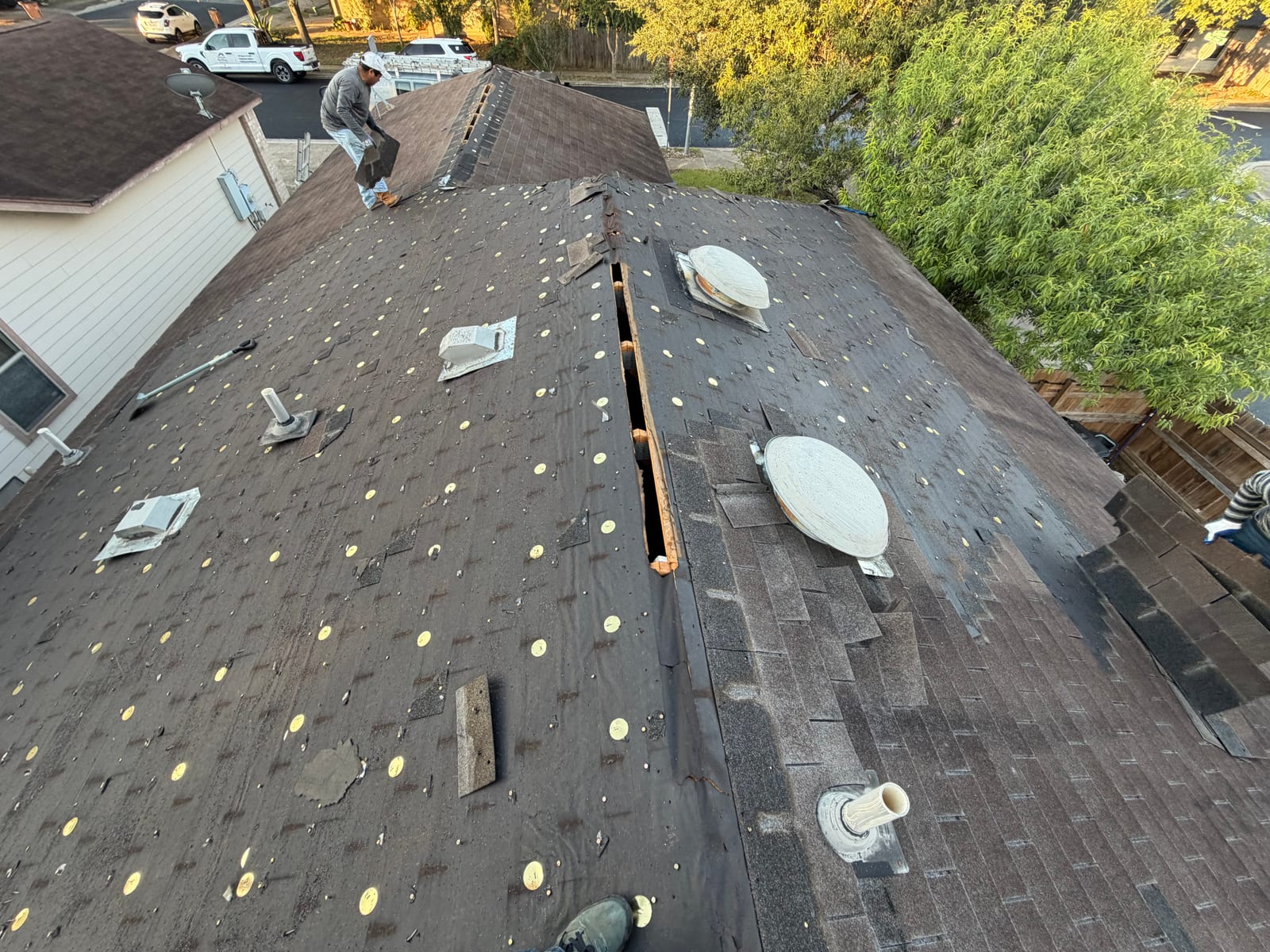 Old roof stripped to the felt, showing several box vents and pipe penetrations scattered across the slopes