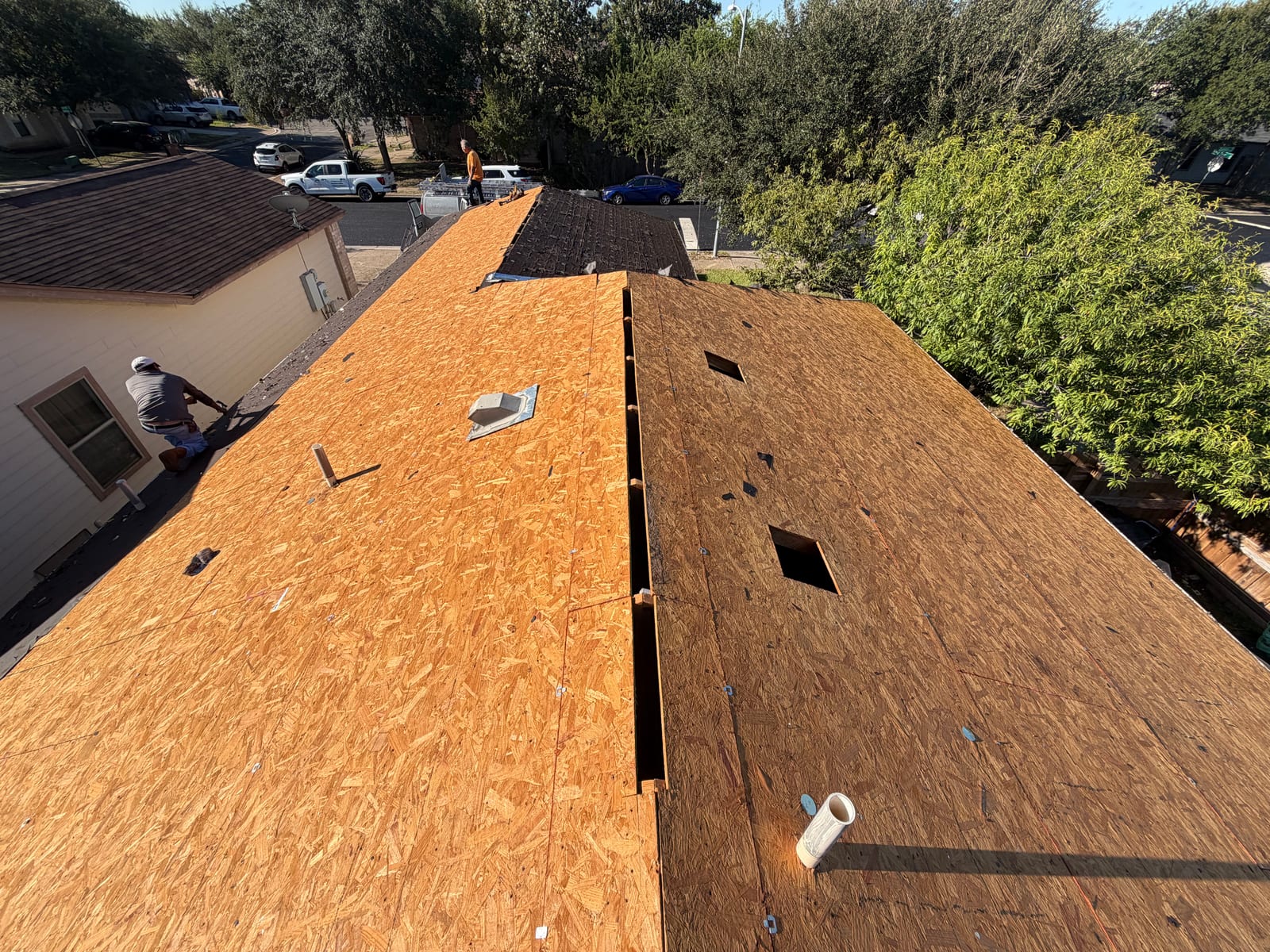 Roof torn off to bare OSB decking, with the old vent openings visible and the ridge cut open for ventilation