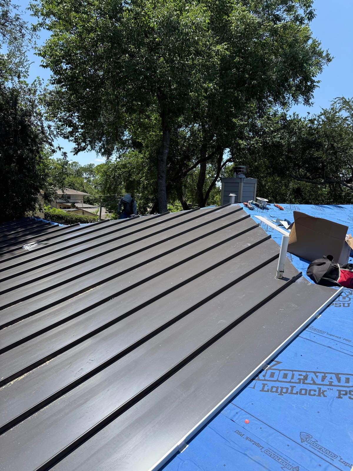 Dark bronze standing seam metal panels on the completed first-story roof
