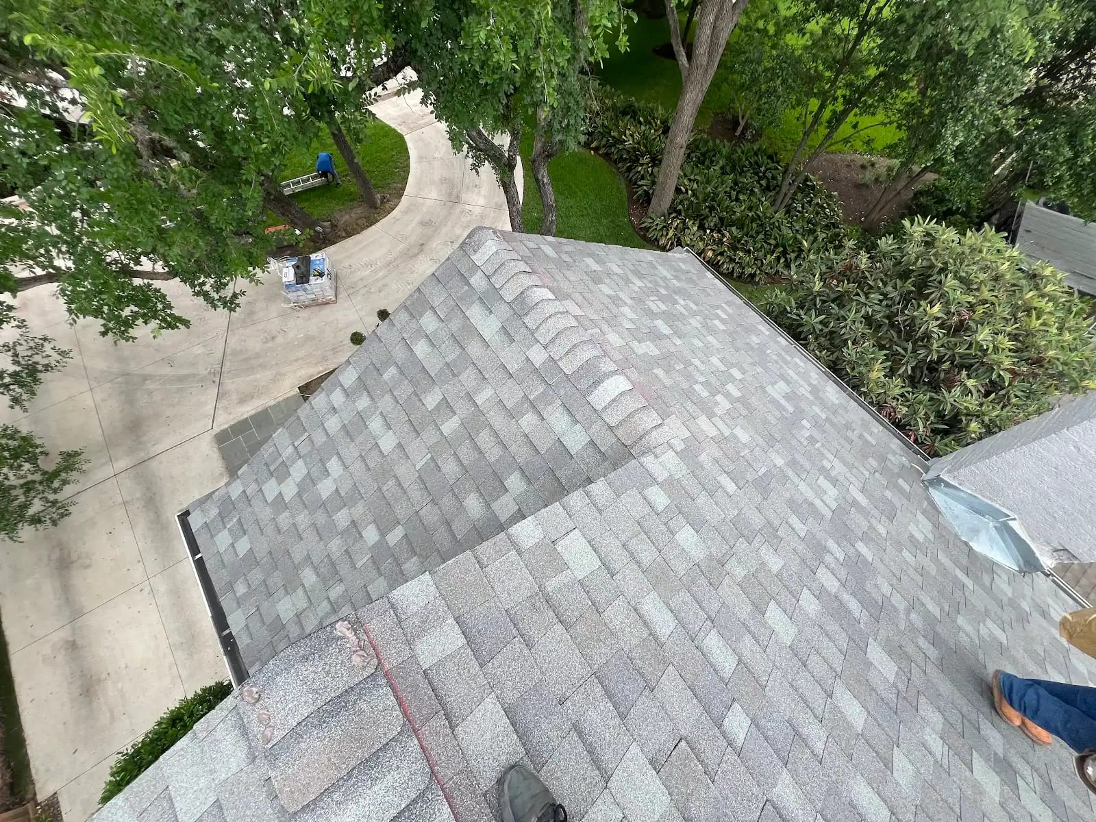 Hip and ridge cap shingles wrapping the corner of the new roof, seen from above