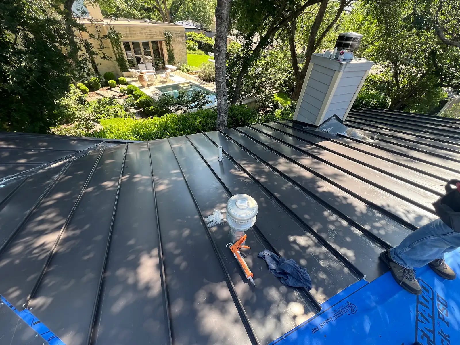 Standing seam panels sealed around the chimney of the first-story roof
