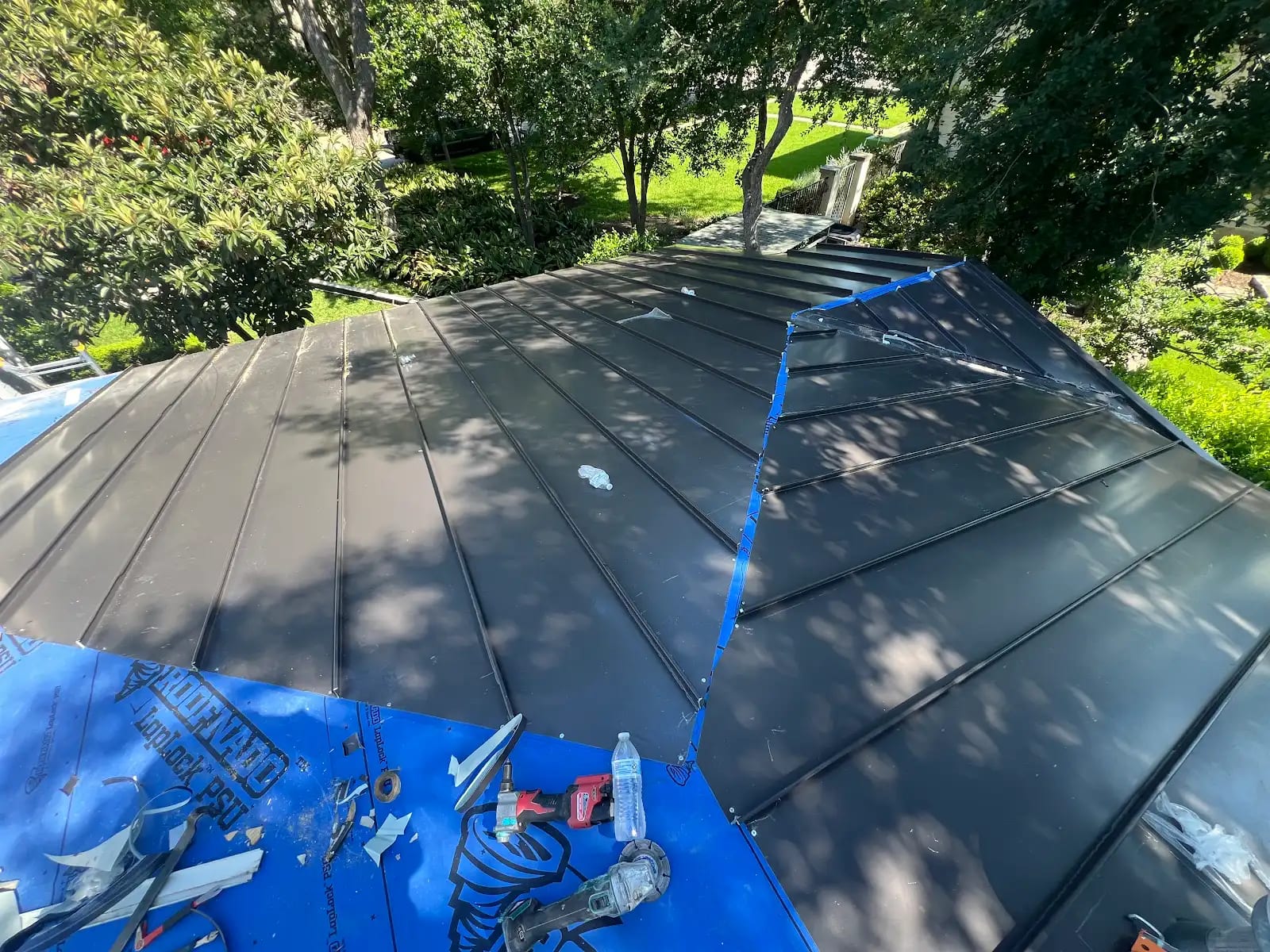 Standing seam metal panels being installed over blue self-adhering underlayment